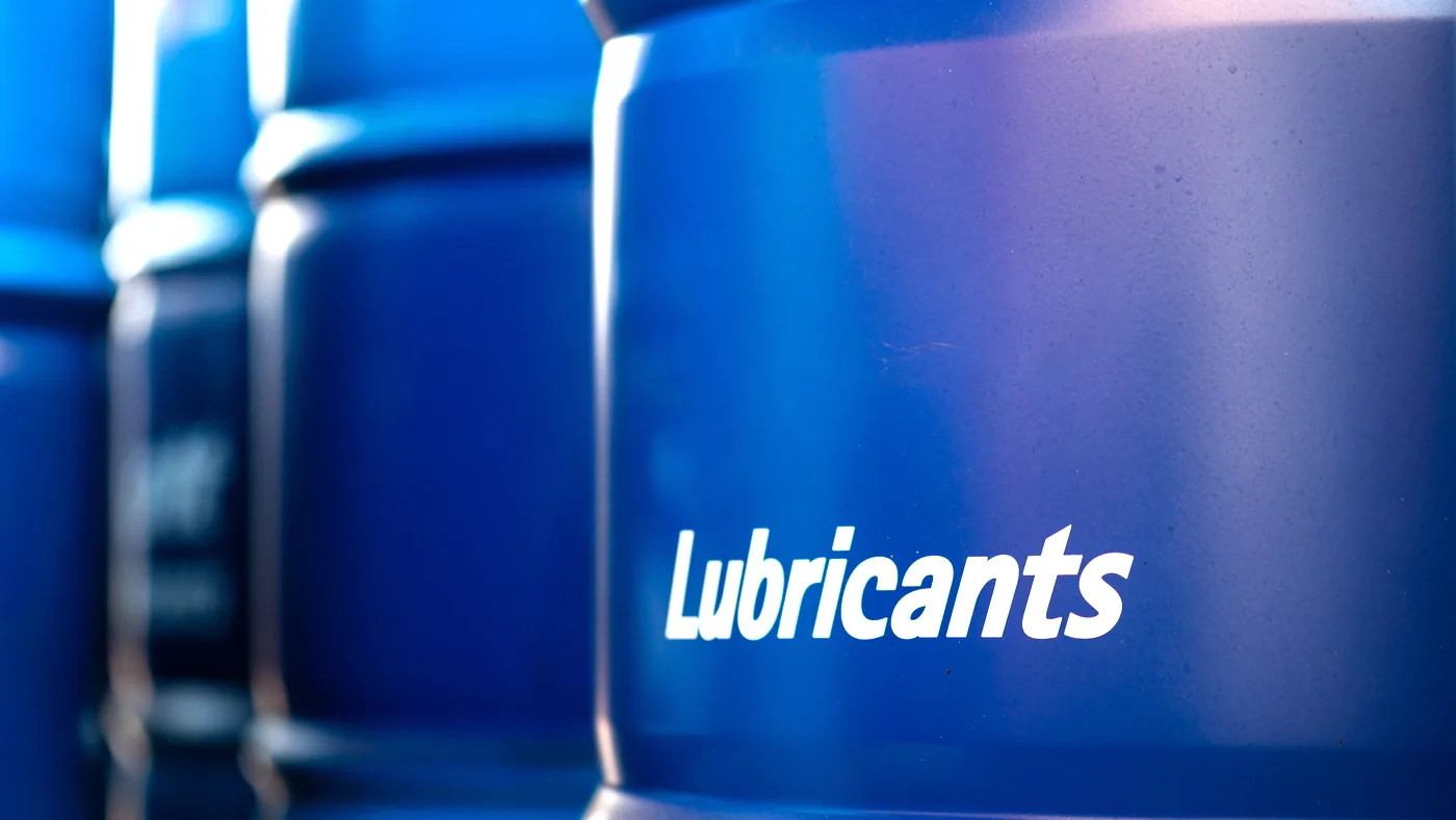 Cilindros de distintas marcas de lubricantes industriales apilados en un almacén