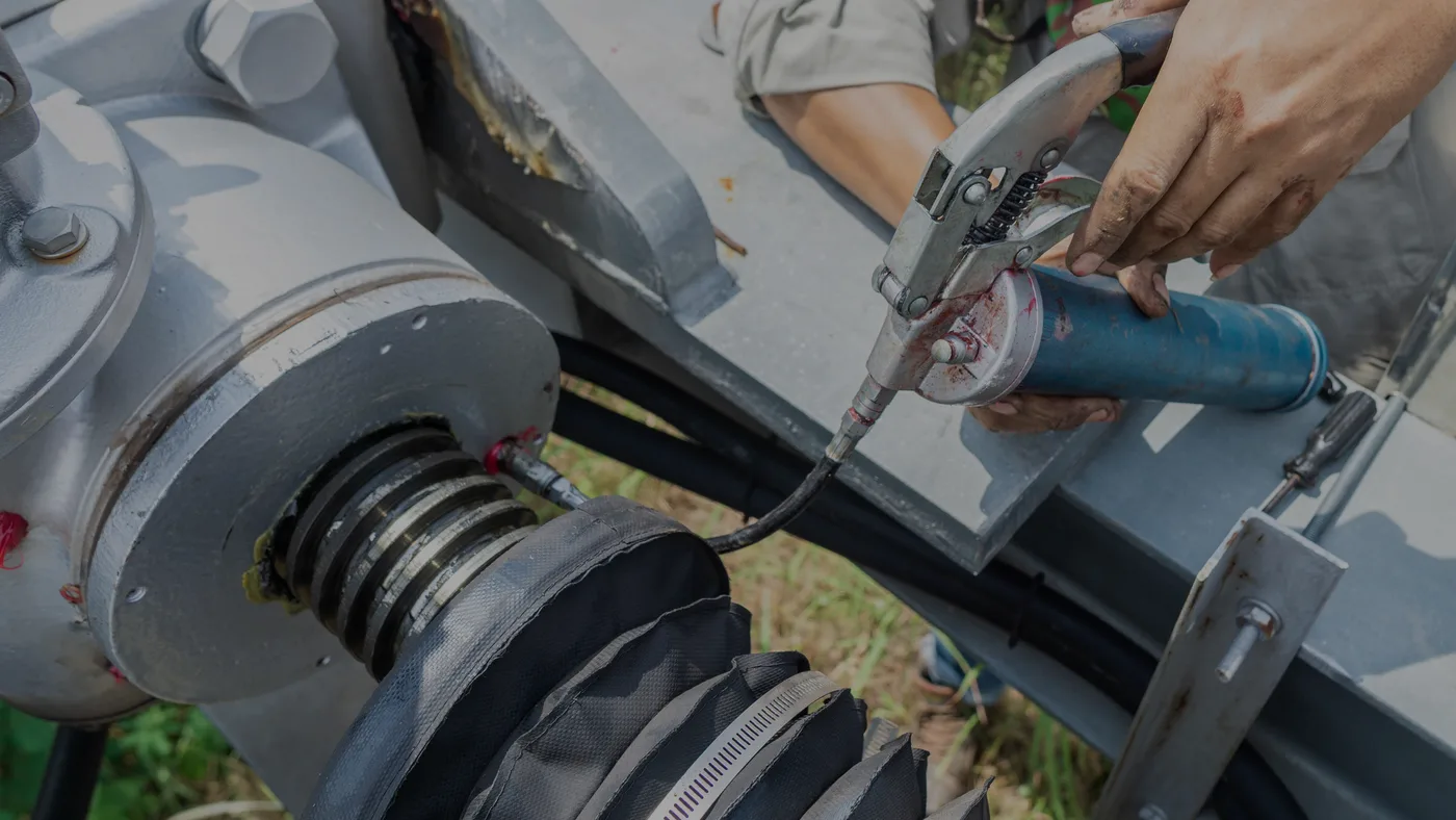 Técnico aplicando grasa con engrasadora en un equipo, uno de los tipos de lubricantes industriales que pide cada sistema